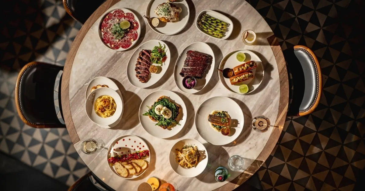 Mesa de Sabine vista desde arriba con carpaccio, cortes, costillas ahumadas, pasta y burrata